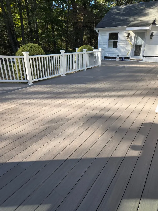 New deck with white railing and siding exterior.